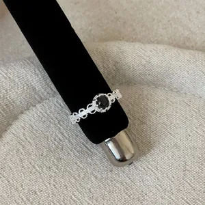 Close-up of a vintage French style silver-tone ring featuring a black stone and lace openwork.