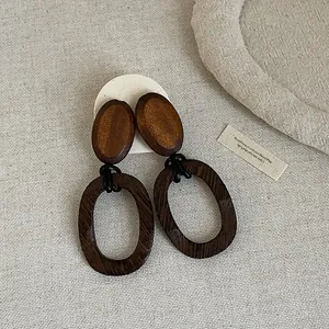 Detailed macro view of retro oval wooden drop earrings on linen background