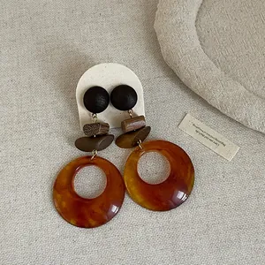 Detailed view of vintage wooden and resin patchwork drop earrings with amber finish