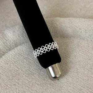 Detailed macro view of an intricate silver lace openwork metal ring on display stand