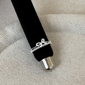 Detailed macro view of a silver French style lace hollow bow ring on black velvet stand
