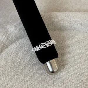 Detailed macro view of an intricate silver lace hollow filigree ring on a black stand