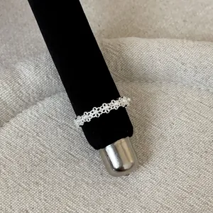 Close-up of delicate silver lace filigree ring with pearls on black display mandrel.