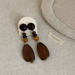 Detailed macro view of vintage wooden patchwork dangle earrings with large teardrop pendants