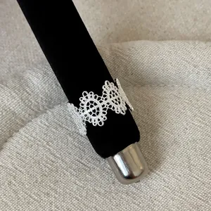 Detailed view of a silver French-style lace openwork metal ring on a black velvet display rod