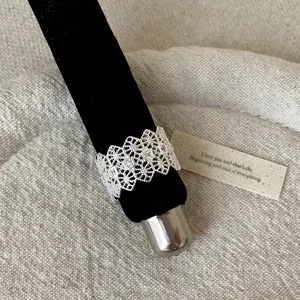 Close-up detail of a silver-toned French lace cutout ring with square zirconia stones.