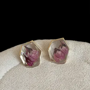 Macro view of vintage hexagonal earrings with pink dried flowers in clear resin.