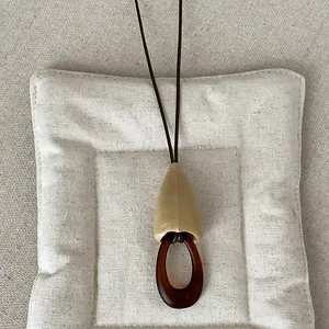 Macro detail of a vintage amber geometric resin pendant on a long dark necklace cord