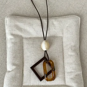 Detailed close-up of a vintage amber resin geometric pendant necklace on a brown cord.