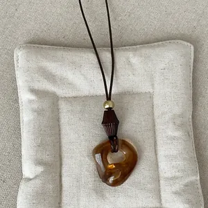 Detailed close-up of the vintage amber geometric resin pendant on long neck cord