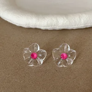 Gros plan de boucles d'oreilles fleur en résine transparente avec strass rose vif.