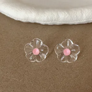 Gros plan de boucles d'oreilles fleurs en résine transparente avec centre rose et plis.