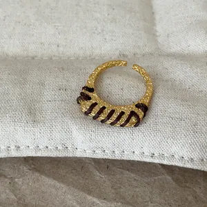 Detailansicht des strukturierten Goldrings mit eleganter brauner Fadenumwicklung.