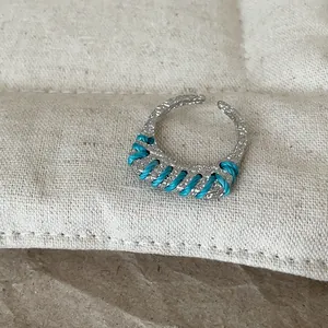 Detailaufnahme eines silbernen Rings mit türkisfarbener Fadenwicklung