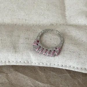Detailansicht eines silbernen texturierten Metallrings mit rosa Fadenumwicklung.
