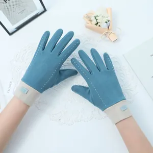 Close-up of stylish teal women's winter gloves with contrast stitching and warm cuffs