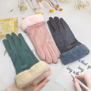 Close-up of warm suede gloves with faux fur trim in pink, green, and grey