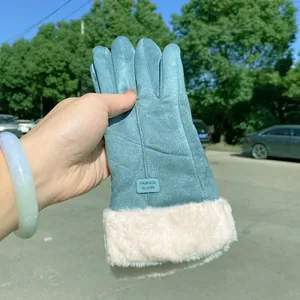 Close-up detail of teal suede winter glove with thick white faux fur lining and label.