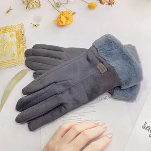 Close-up of grey suede winter gloves with plush faux fur cuffs and soft inner lining