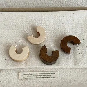 Detailed view of vintage chubby wooden C-ring stud earrings in light and dark wood tones