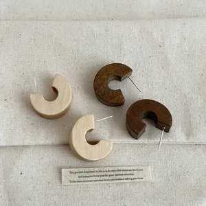 Close-up of retro thick wooden C-hoop earrings in natural and dark finishes