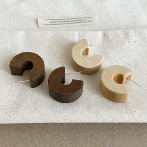 Macro view of retro C-shaped wooden stud earrings in dark and light brown finishes.