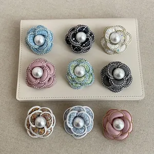 Detailed view of elegant camellia fabric brooches with central pearls in various colors.