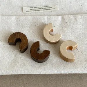 Close-up of vintage C-shaped wooden stud earrings in dark and light wood finishes.
