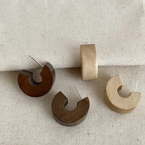 Retro thick wooden C-hoop stud earrings in dark and light wood tones on linen cloth