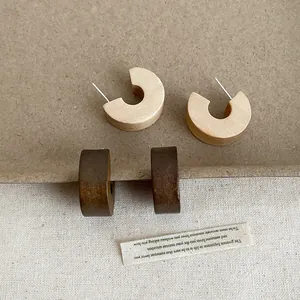 Detail of vintage chunky wooden C-hoop earrings in natural and dark brown colors