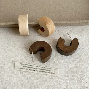 Close-up view of vintage thick wooden C-shaped stud earrings in brown and tan