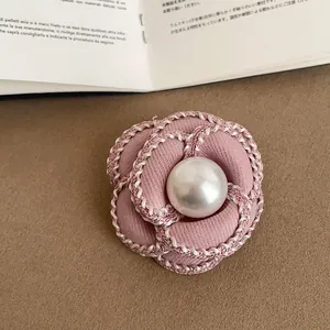 Detailed view of an elegant pink camellia brooch featuring a central pearl and braided edges.