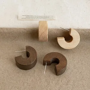 Detail view of vintage chunky wooden C-shaped stud earrings in light and dark wood.