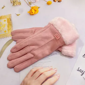 Detail view of soft pink suede winter gloves featuring warm faux fur cuffs and fashion tag.