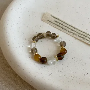 Detailed view of handmade tiger eye and clear crystal beaded elastic ring on a textured plate