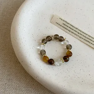 Detailed view of tiger eye and crystal beaded elastic ring on a ceramic plate.