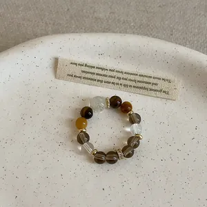 Detailed view of a handmade tiger eye and crystal beaded elastic ring on a ceramic tray