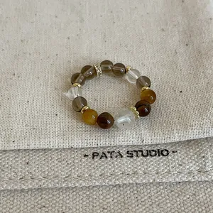 Macro view of elastic tiger eye and quartz crystal beaded ring on textured fabric