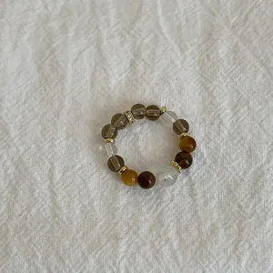 Macro detail of natural tiger eye and crystal beads on a textured fabric background