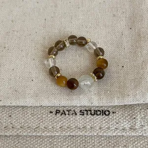 Close-up detail of a handmade beaded elastic ring featuring tiger eye and crystal stones