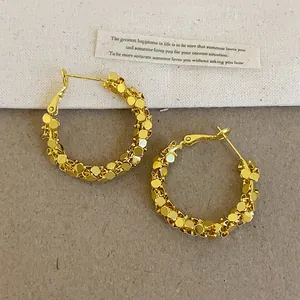 Gros plan de boucles d'oreilles créoles dorées avec un effet argent concassé