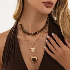 Detailopname van vintage gelaagde ketting met tijgeroogkralen en hartvormige hangers.