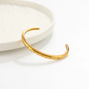 Gros plan d'un élégant bracelet jonc en acier doré avec gravures d'étoiles brillantes