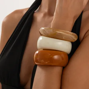 Primer plano de brazaletes de resina retro con efecto mármol en el brazo del modelo