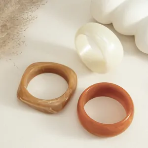 Primer plano de brazaletes de resina jaspeada con formas variadas y texturas ámbar cálidas.