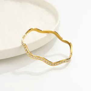 Vue détaillée d'un bracelet jonc ondulé en acier inoxydable doré orné de brillants strass