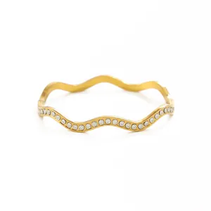 Détail d'un bracelet jonc ondulé en acier inoxydable plaqué or 18 carats avec cristaux clairs