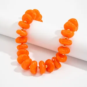 Nahaufnahme einer orangefarbenen Harzperlenkette mit schicken goldenen Perlen.