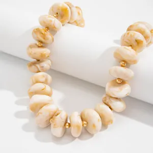 Nahaufnahme einer Harzperlenkette mit Marmormuster und eleganten goldenen CCB-Abstandshaltern.