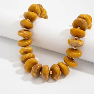 Makro-Detail von klobigen bernsteinfarbenen Harzperlen und Gold-Abstandshaltern an Kette